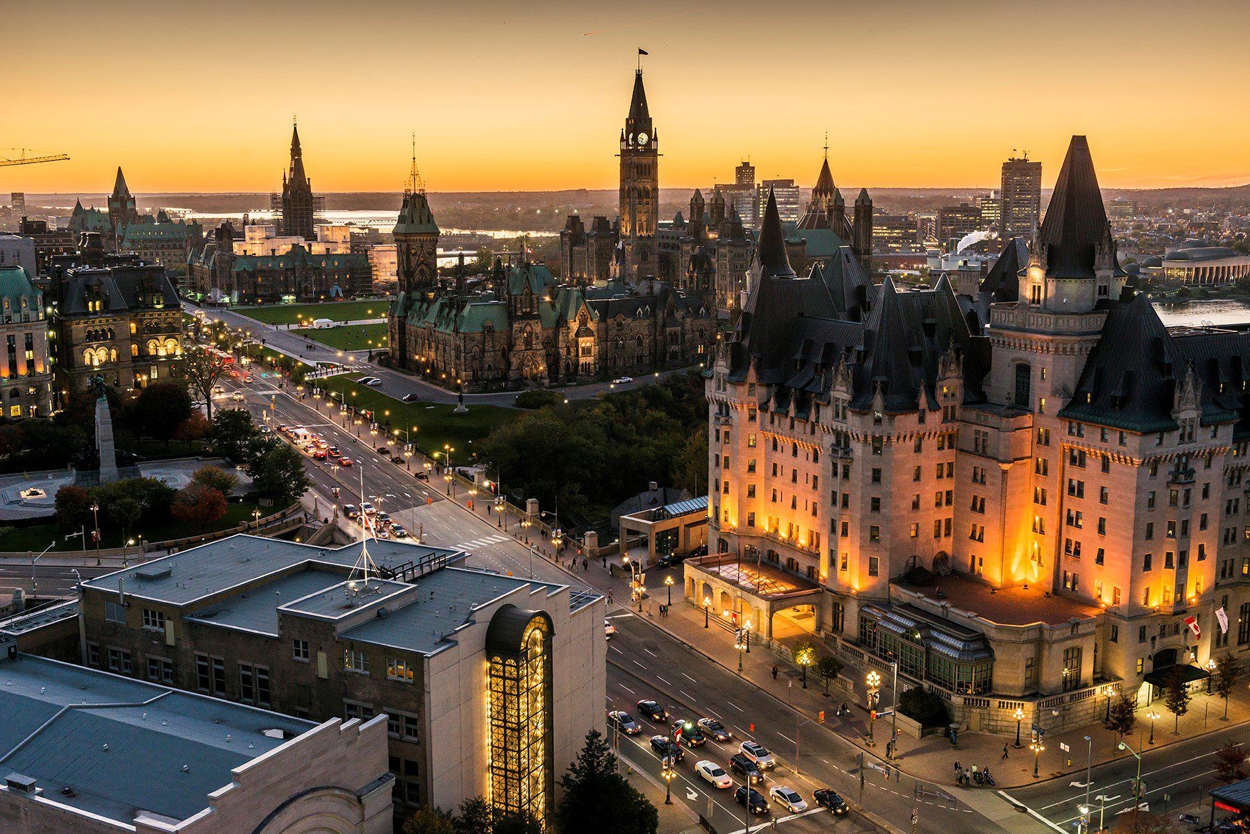 Aerial view of a cityscape featuring illuminated historic buildings and a sunset sky.