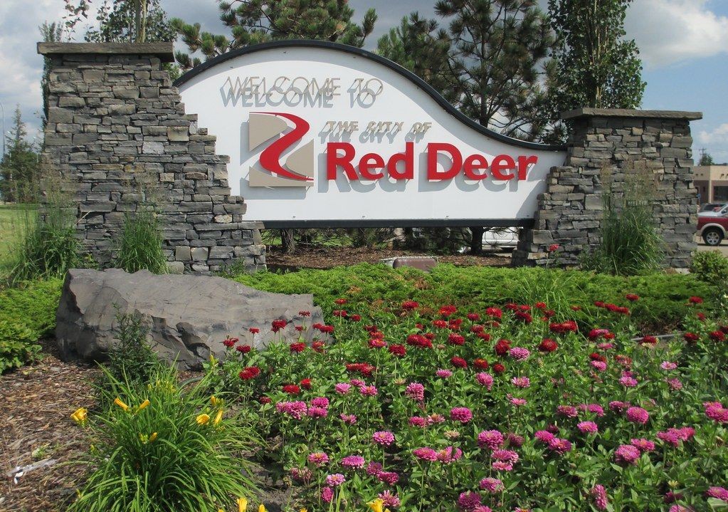 Welcome sign for the city of Red Deer surrounded by a stone structure and blooming flowers.