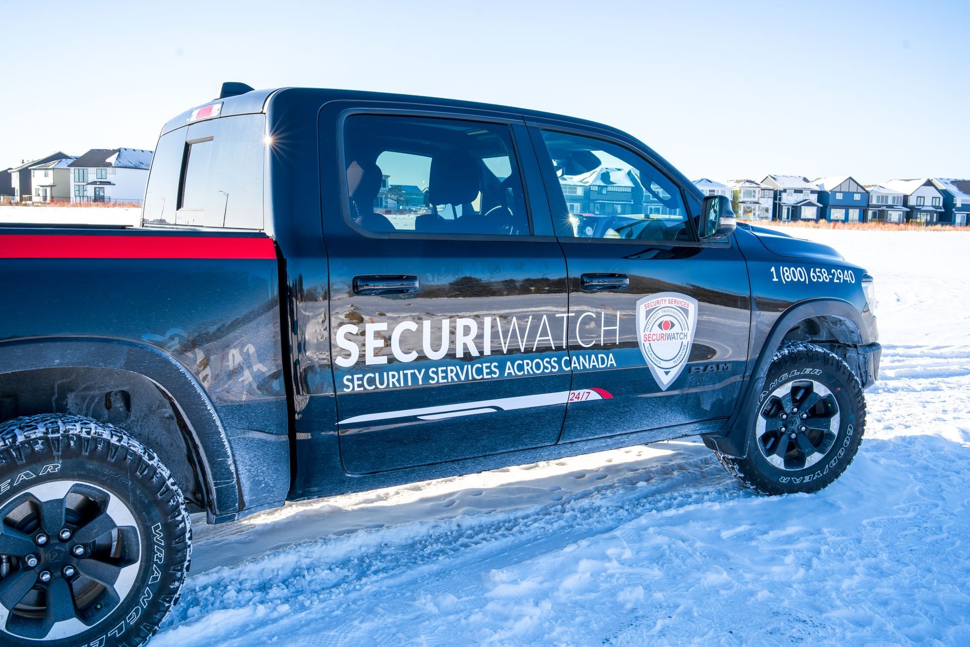 Black pickup truck labeled 'SecuriWatch Security Services Across Canada' parked on snow.