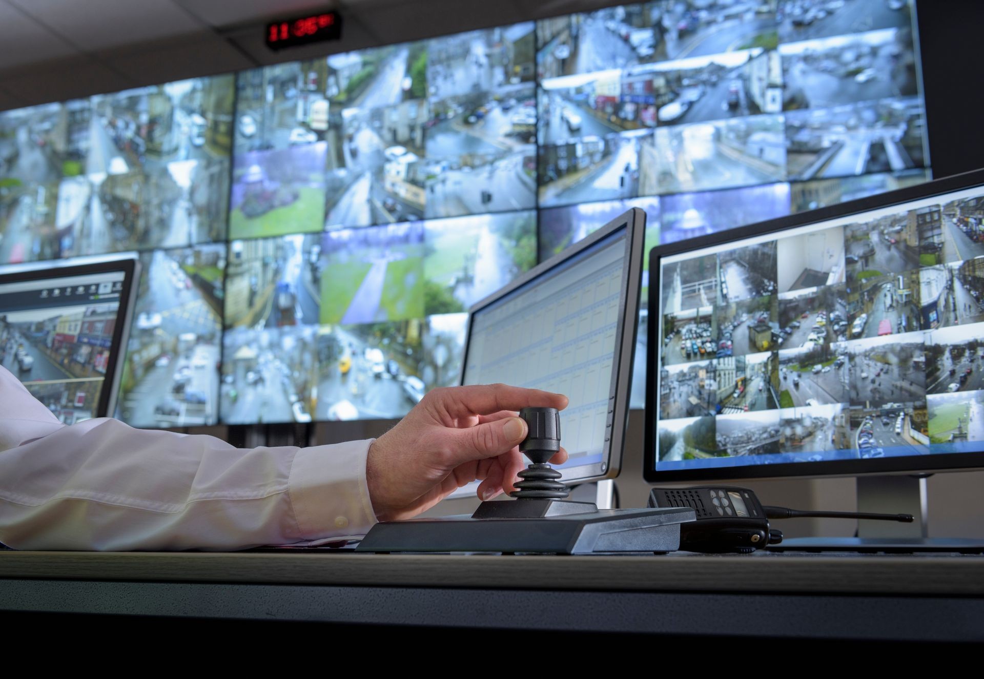 Detail of hand on camera control joystick in control room with video wall